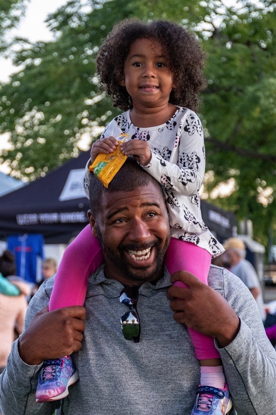 A child sitting on her father's shoulders, happy because of therapy